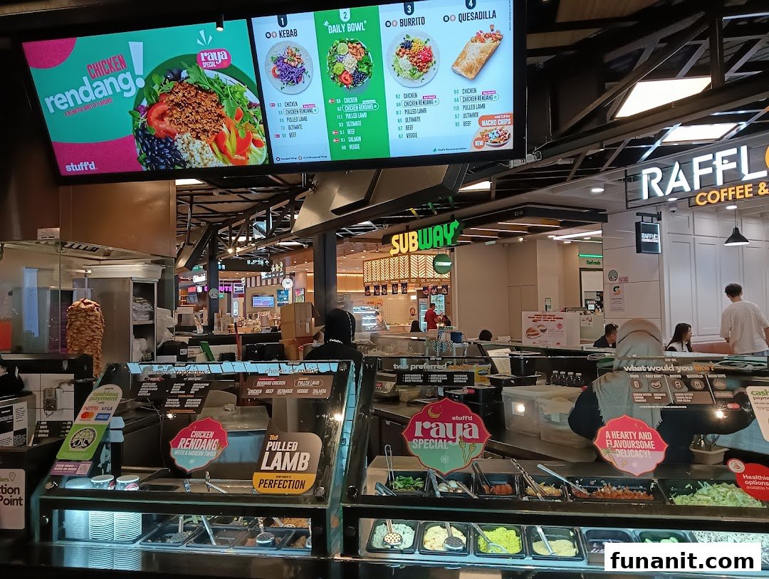 A vibrant food stall interior featuring a digital menu board displaying kebabs, bowls, burritos, and quesadillas.