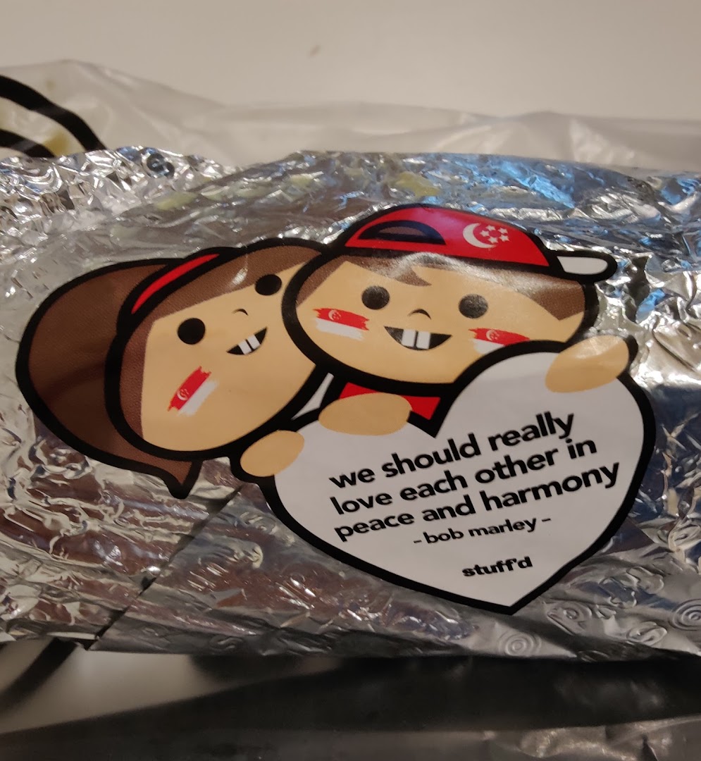 A foil-wrapped food item from Stuffd with a sticker featuring cartoon characters and a Bob Marley quote.