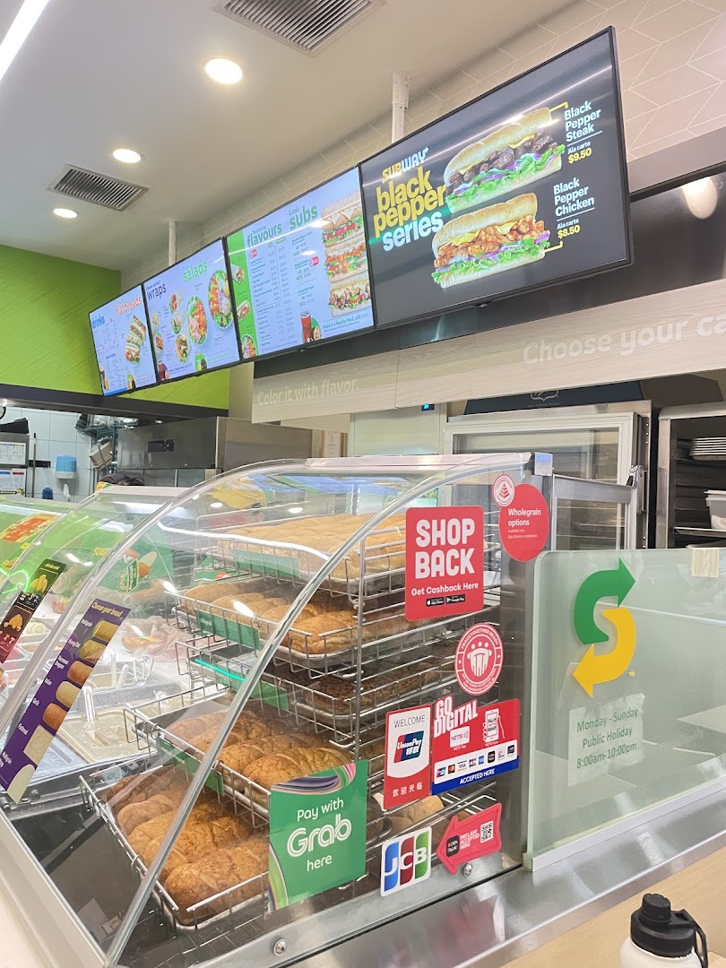 Interior view of Subway counter with digital menu boards displaying subs, salads, and drinks.