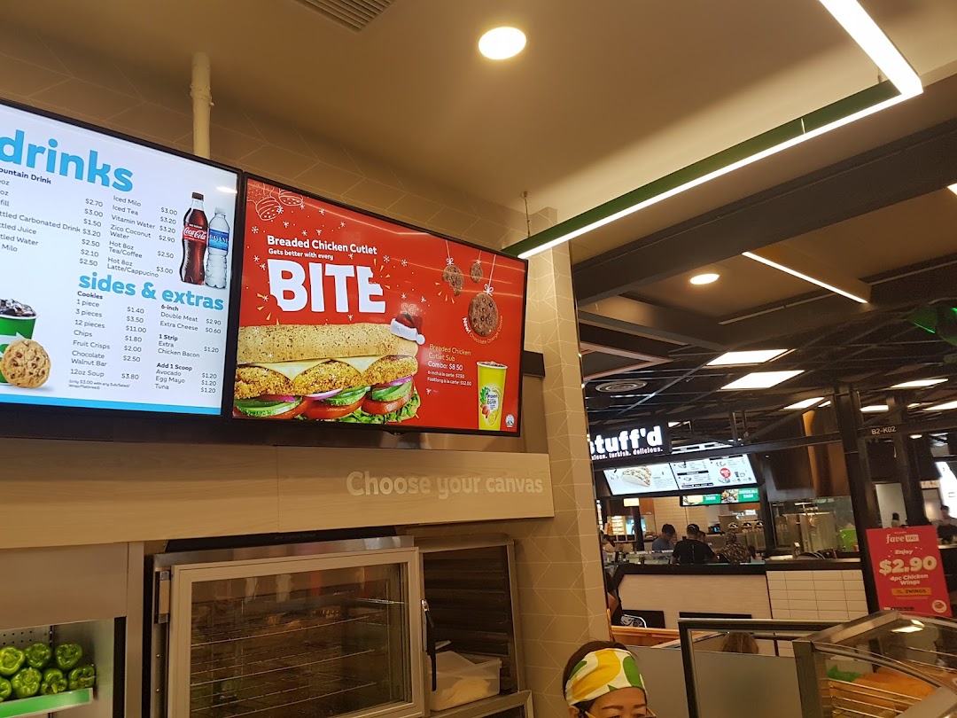 Interior view of Subway featuring digital menu boards, fresh ingredients, and counter area.