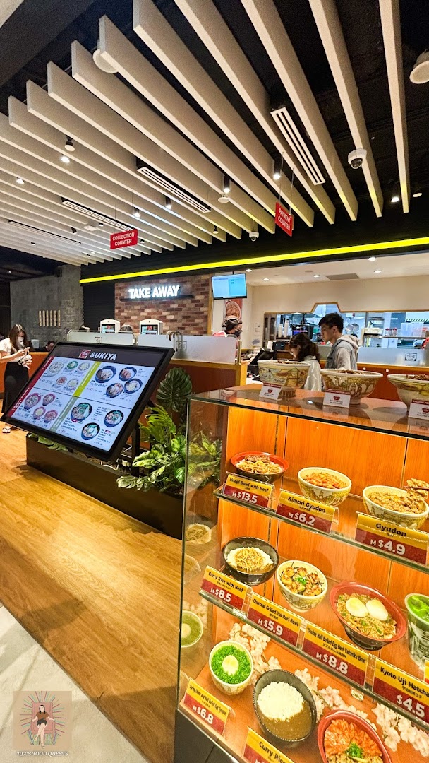 Interior view of Sukiya, featuring food display models, a digital menu, and the service counter.