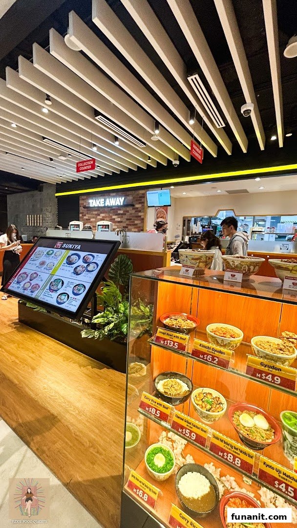 Interior view of Sukiya, featuring food display models, a digital menu, and the service counter.