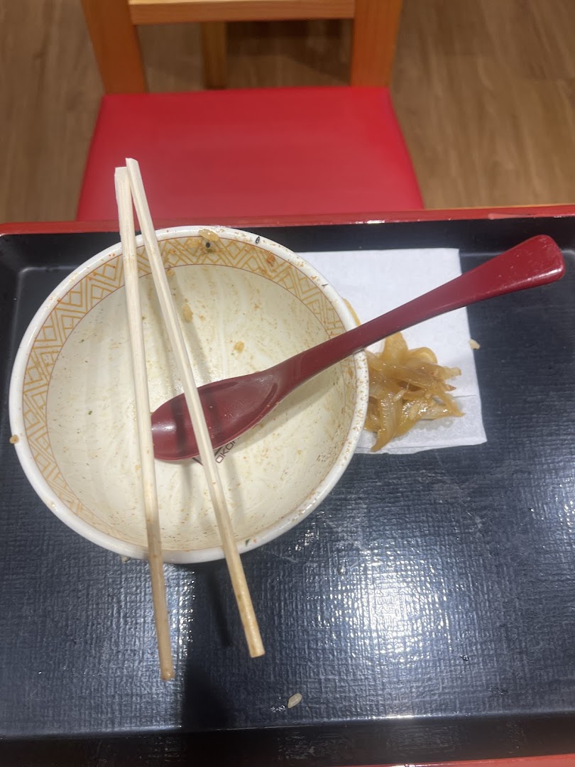 An empty bowl with chopsticks and spoon on a tray after a satisfying meal at Sukiya.