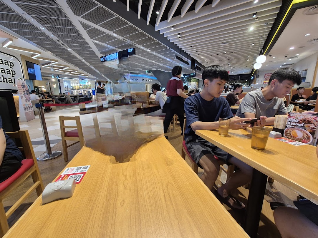 Customers dining at Sukiya, enjoying Japanese comfort food in a bright, spacious setting.