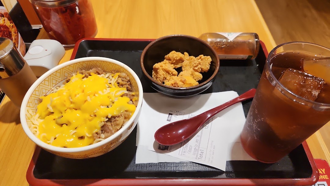A delicious Sukiya meal featuring cheesy gyudon, crispy karaage, and refreshing iced tea on a tray.