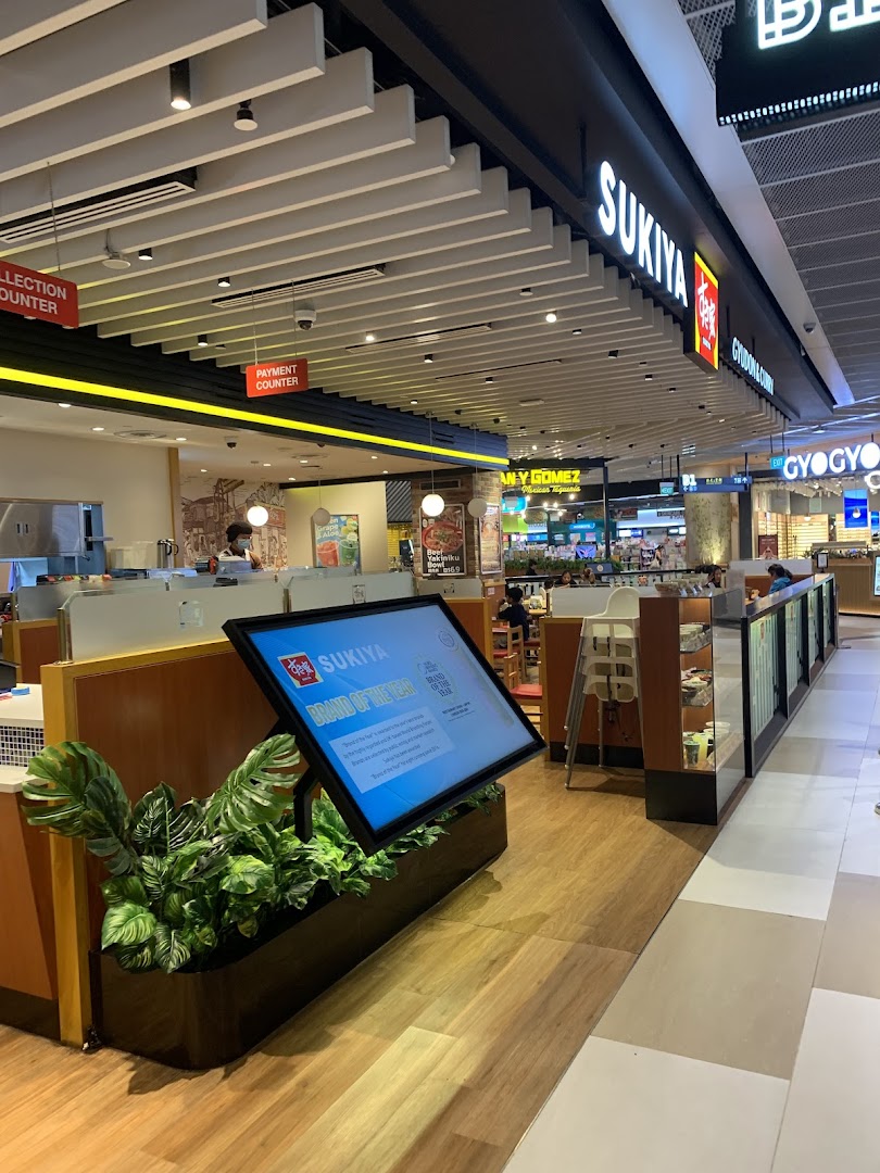 Interior view of Sukiya, a Japanese restaurant, featuring its counter, seating area, and digital display.