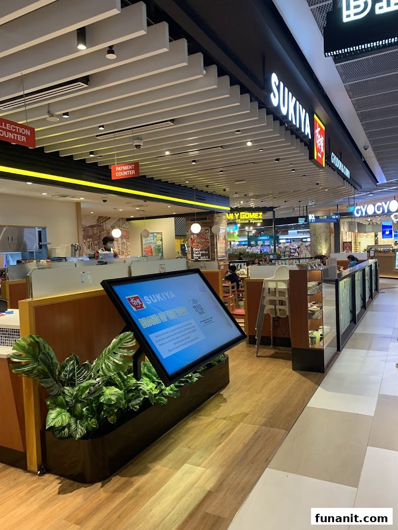 Interior view of Sukiya, a Japanese restaurant, featuring its counter, seating area, and digital display.