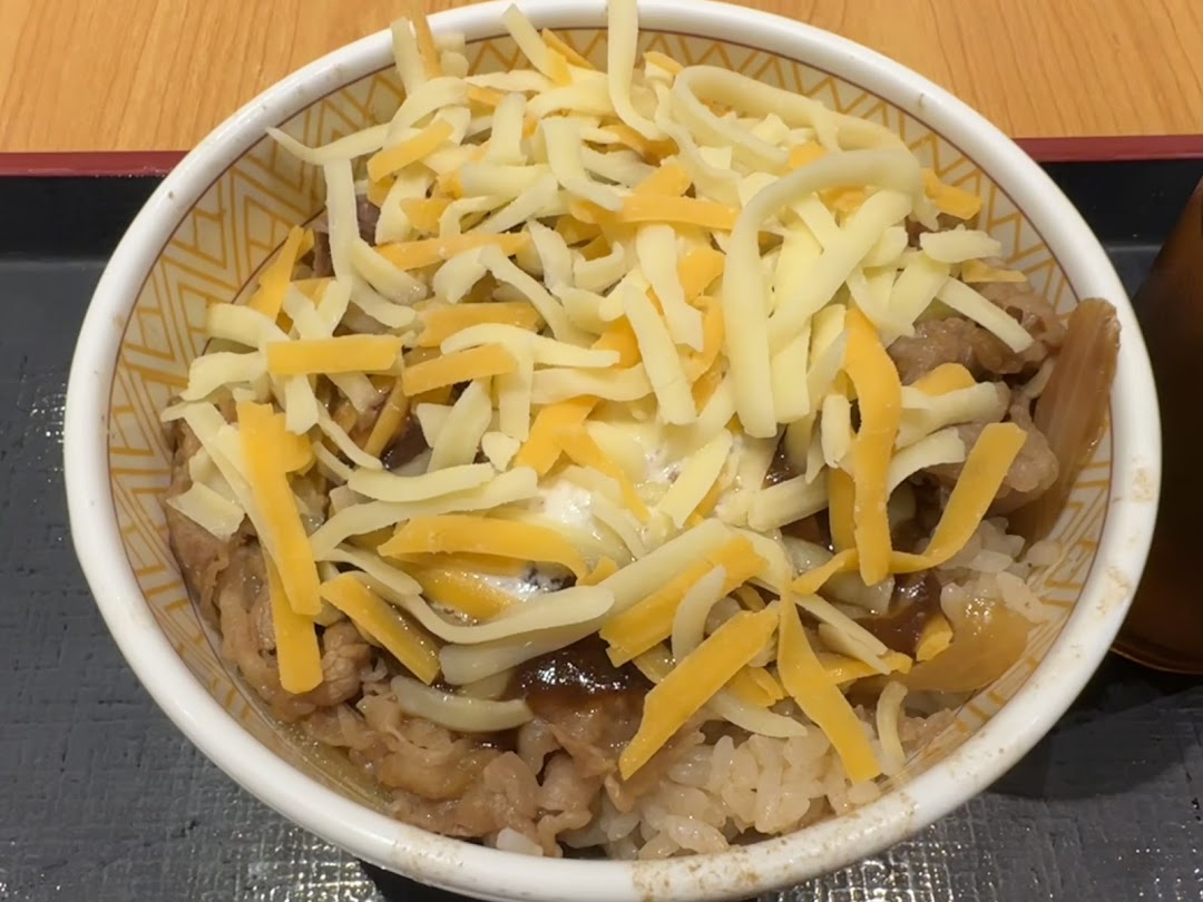 A close-up of a delicious Sukiya Gyudon bowl topped with shredded cheese.