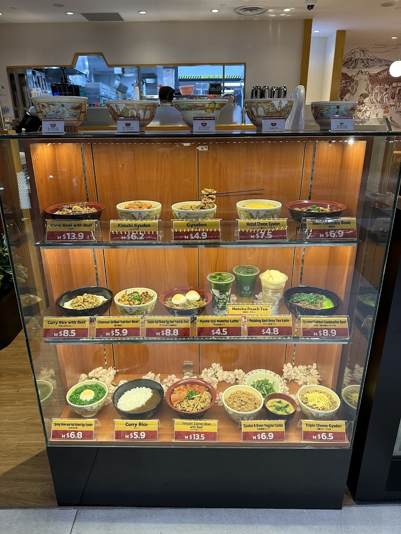 A display case showcasing various Japanese food models and drinks with prices at Sukiya.