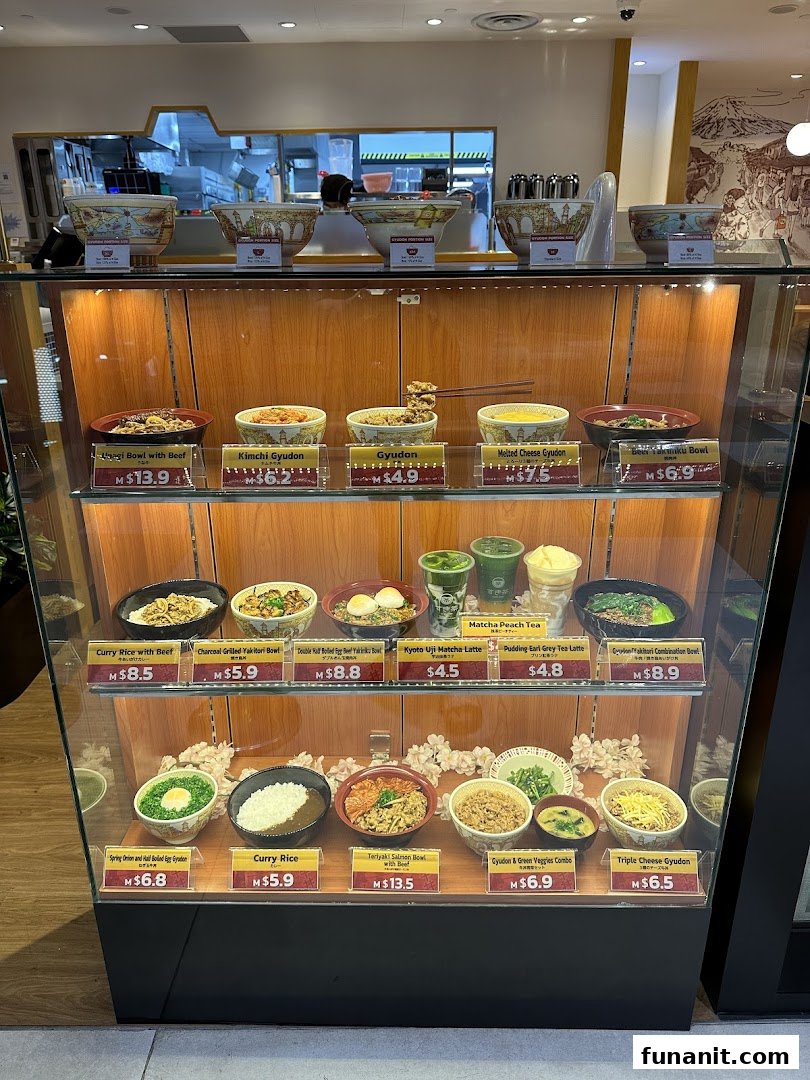 A display case showcasing various Japanese food models and drinks with prices at Sukiya.
