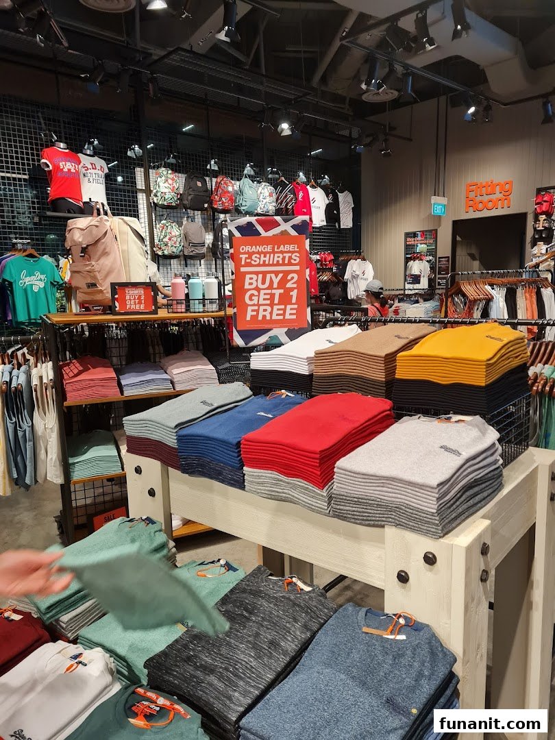 Interior view of a Superdry store showcasing folded apparel, backpacks, and a 'Buy 2 Get 1 Free' T-shirt offer.