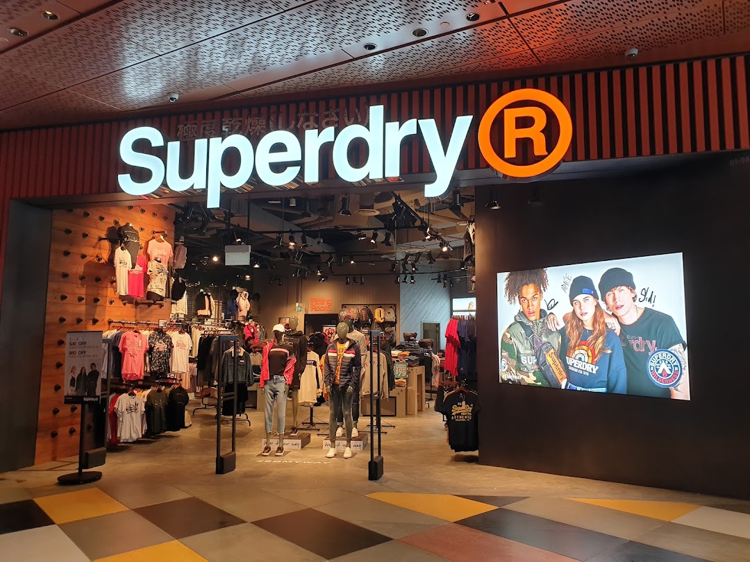The Superdry shop entrance with its illuminated logo, displaying clothing and a large digital screen.
