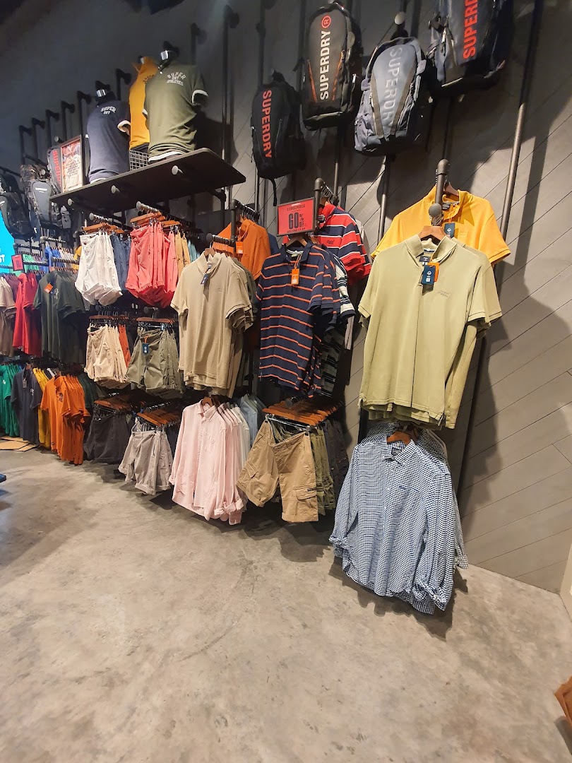 Interior view of Superdry store showcasing a wide range of casual apparel, including polos, shirts, shorts, and backpacks.