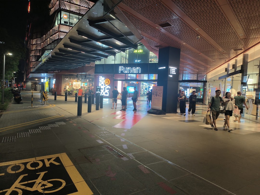Night view of Funan mall entrance with pedestrians and the Superdry store facade illuminated.