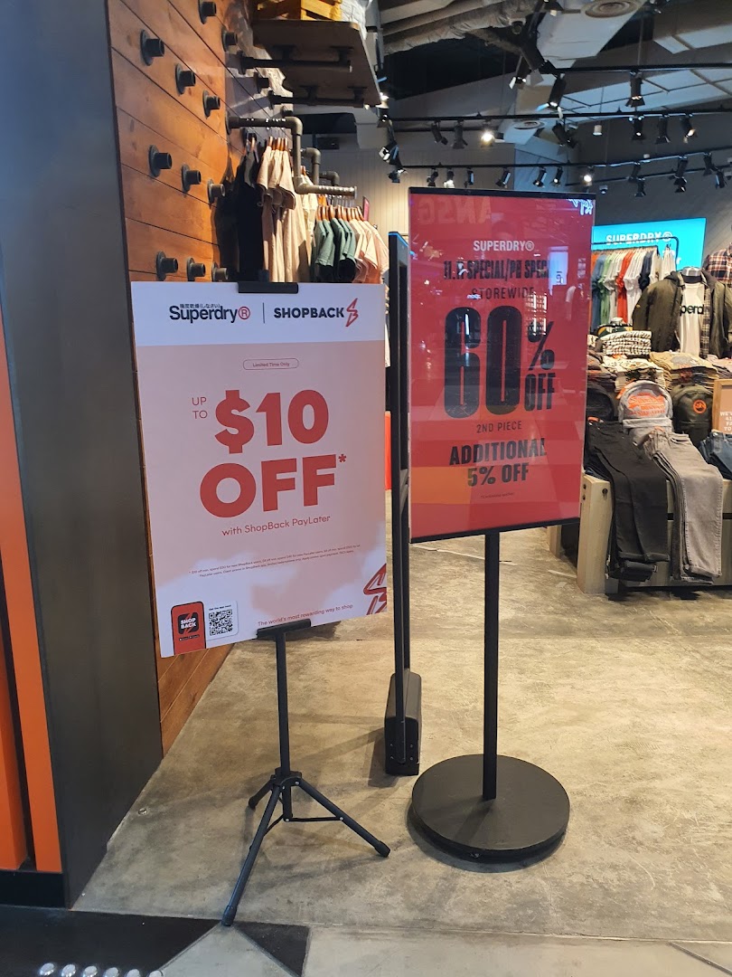 Promotional signs and clothing displays inside a Superdry store, highlighting current offers.