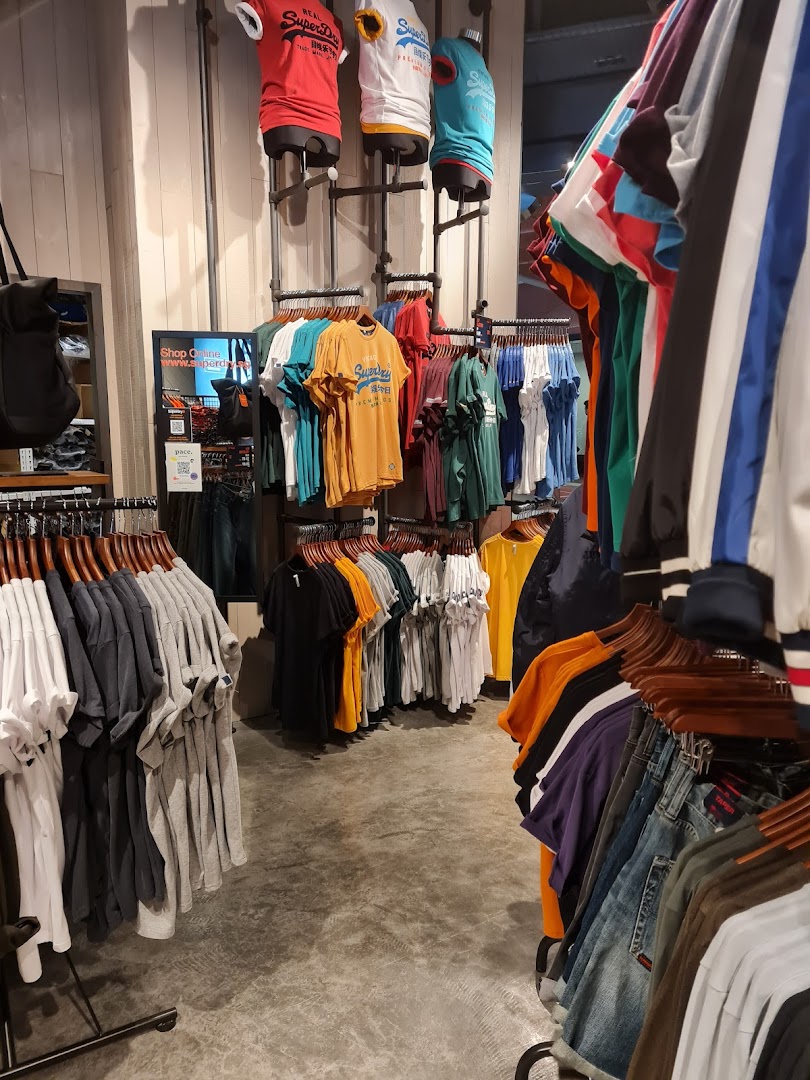 An interior view of a Superdry store showcasing various casual apparel on racks and mannequins.