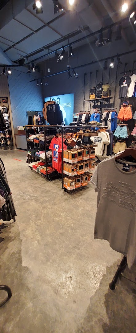 Interior view of a Superdry store showcasing clothing racks, accessories, and a large display screen.