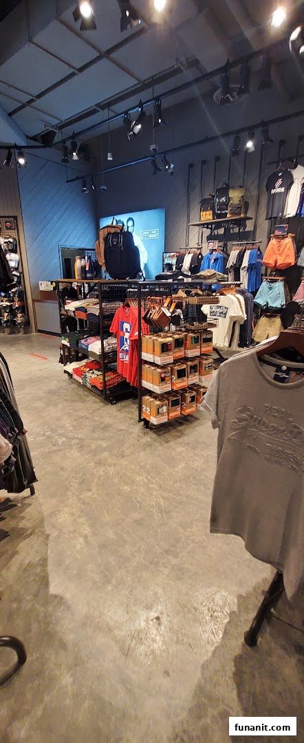 Interior view of a Superdry store showcasing clothing racks, accessories, and a large display screen.