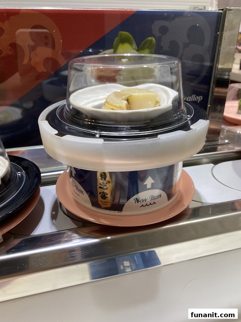 A fresh abalone dish on a conveyor belt at Sushi Express, featuring a 'New Item' label.