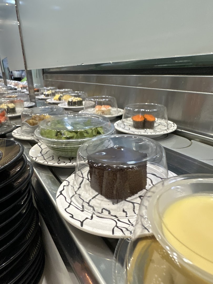 A conveyor belt at Sushi Express showcasing various covered sushi, desserts, and other dishes.
