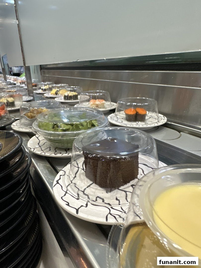 A conveyor belt at Sushi Express showcasing various covered sushi, desserts, and other dishes.