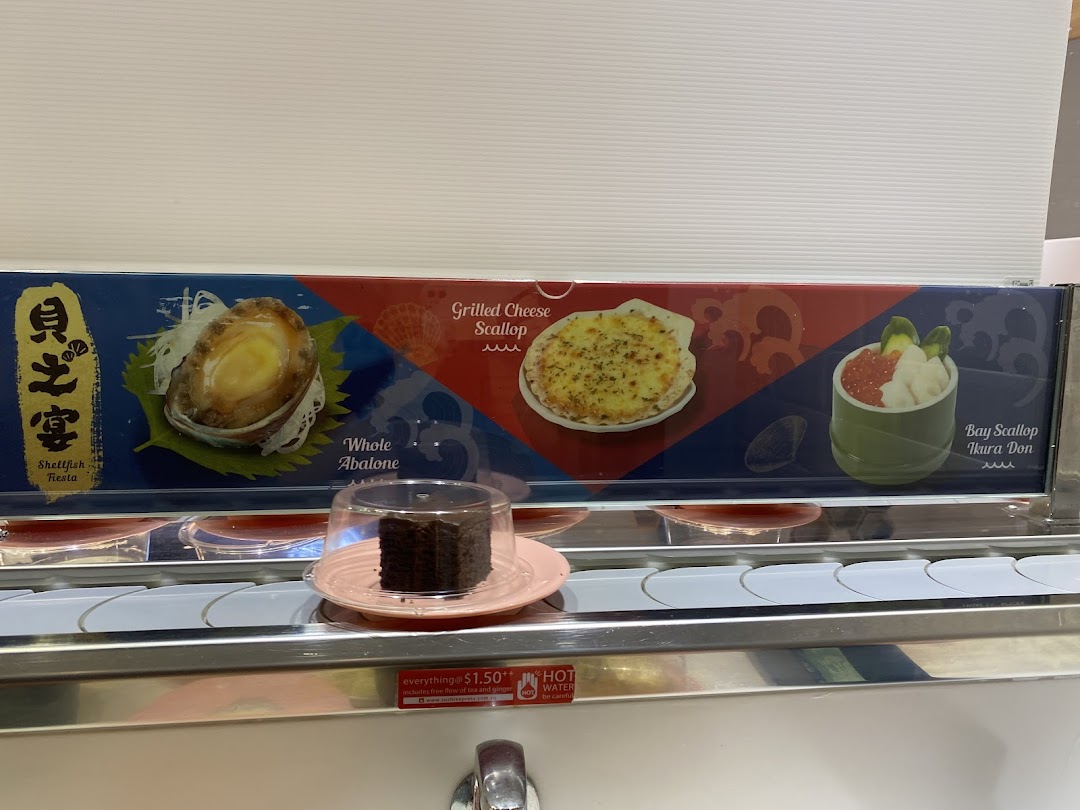 A close-up of Sushi Express's conveyor belt featuring a dessert and a display of premium seafood dishes.