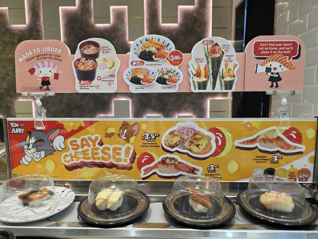A vibrant display of sushi and other dishes on a conveyor belt with menu signs.