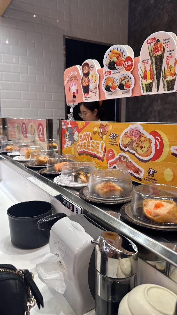 A vibrant interior shot of Sushi Express, showcasing a conveyor belt laden with various sushi dishes.