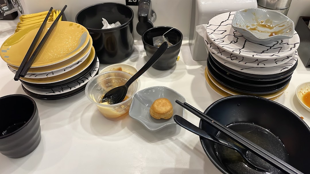 A table at Sushi Express with stacks of used plates, chopsticks, and empty bowls after a meal.