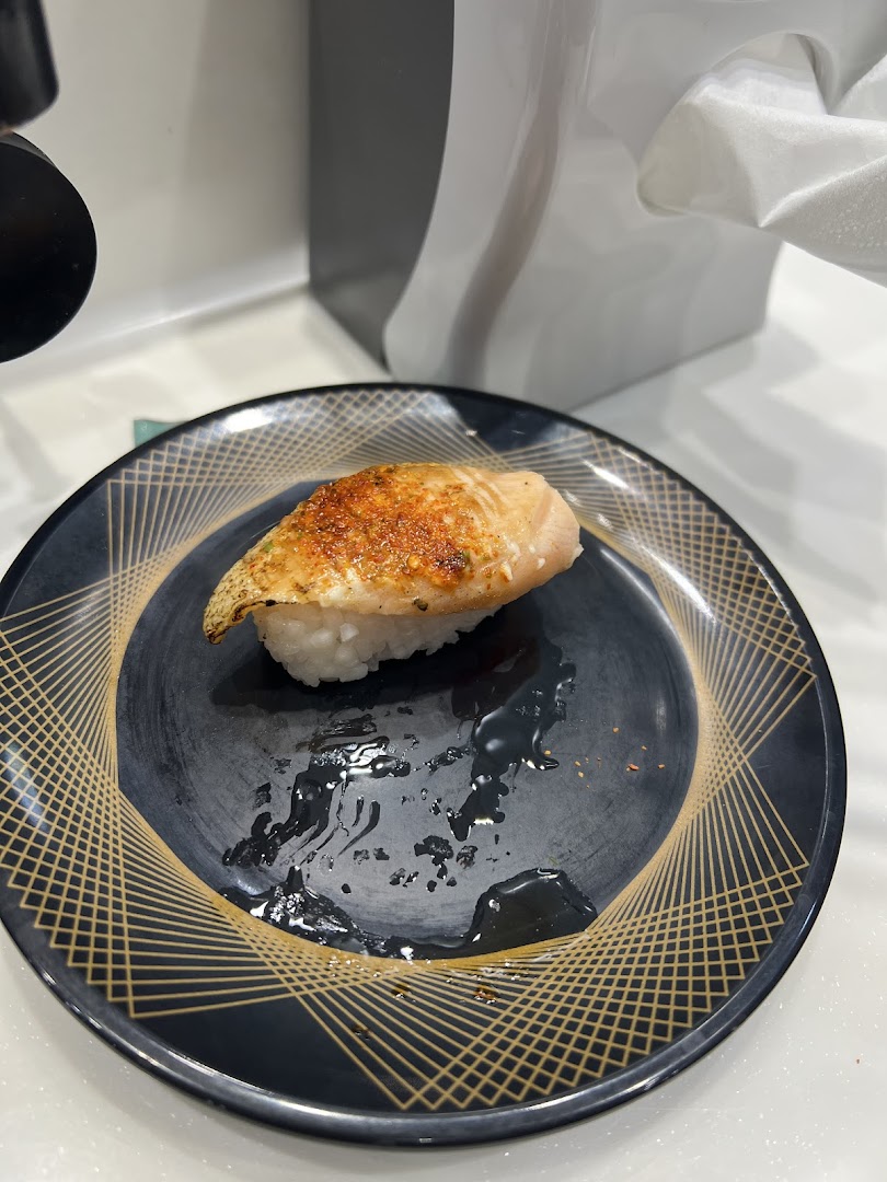 A close-up of a delicious piece of aburi salmon sushi on a decorative plate.