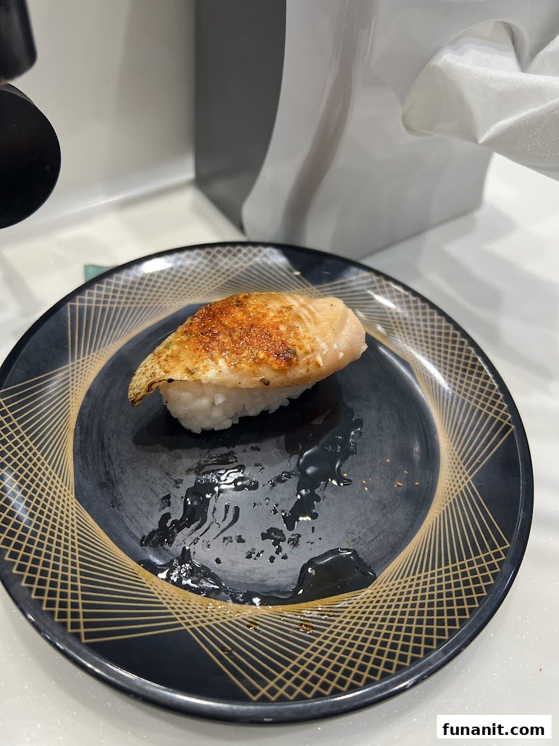 A close-up of a delicious piece of aburi salmon sushi on a decorative plate.