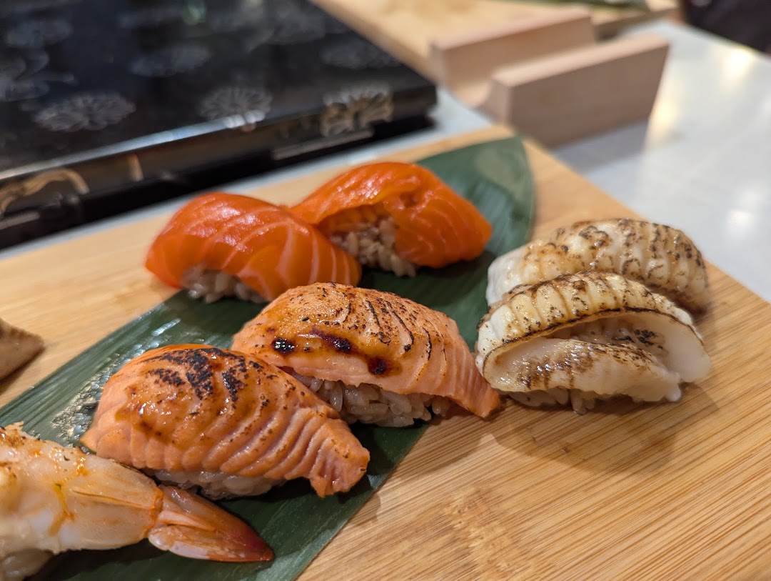 A close-up of various fresh sushi pieces, including salmon and scallop nigiri, served on a wooden board.