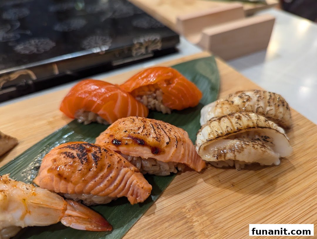 A close-up of various fresh sushi pieces, including salmon and scallop nigiri, served on a wooden board.