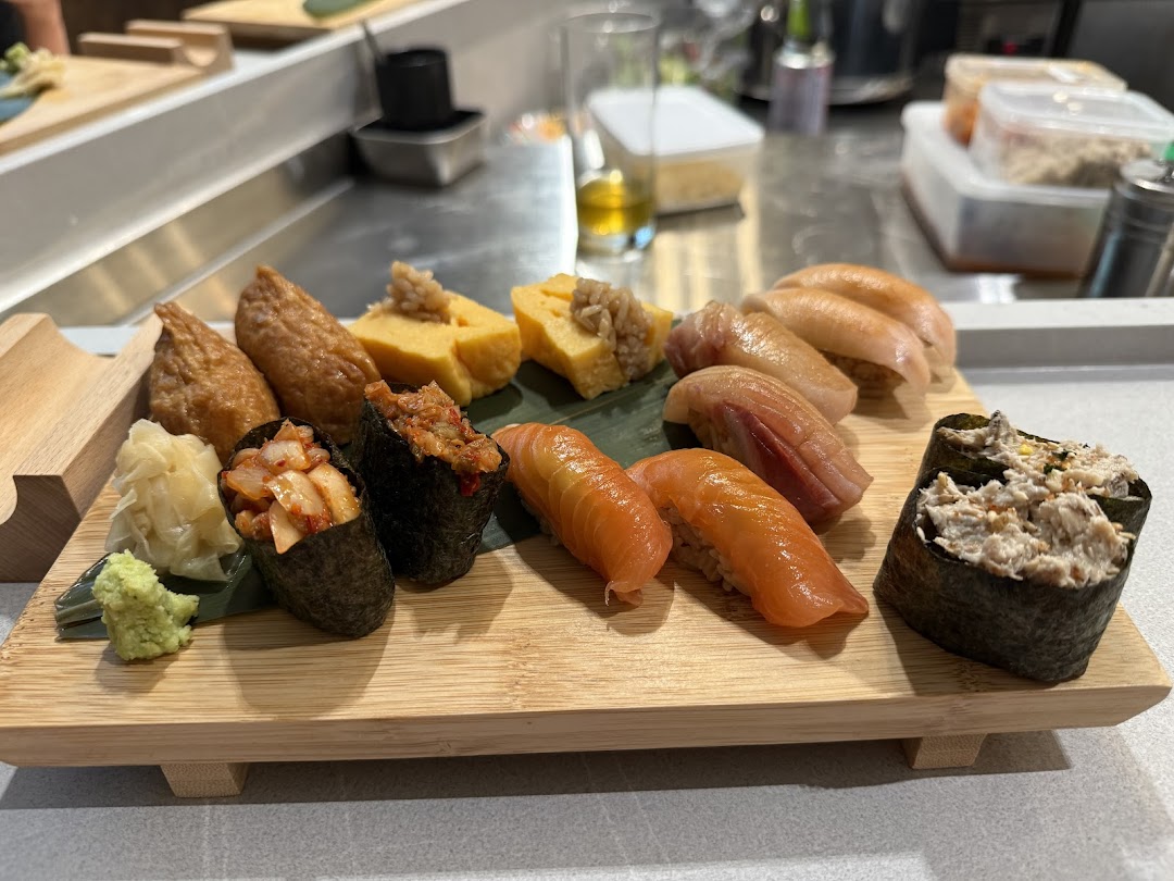 A wooden platter showcasing a variety of freshly prepared sushi, including nigiri, gunkan maki, and inari.