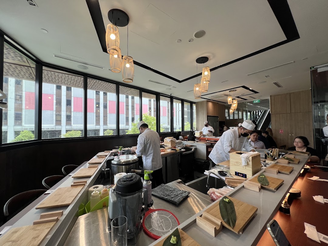 Chefs meticulously prepare fresh sushi at a vibrant counter, offering an engaging dining experience at Sushi Zushi.