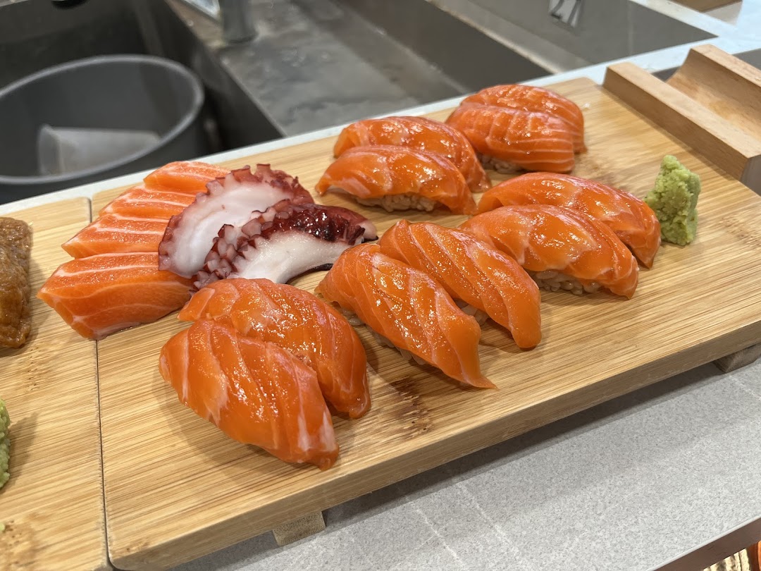 A wooden board showcasing an assortment of fresh salmon nigiri, salmon sashimi, and octopus sashimi.