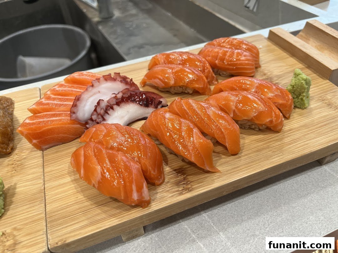 A wooden board showcasing an assortment of fresh salmon nigiri, salmon sashimi, and octopus sashimi.