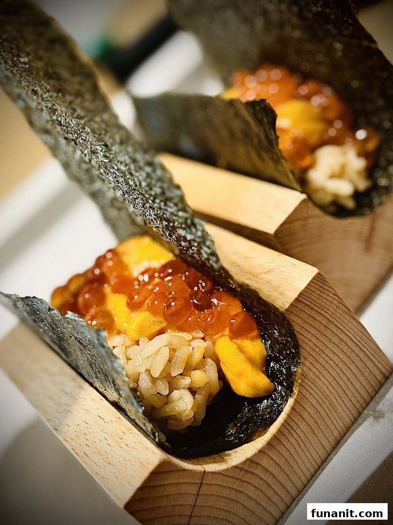 Two exquisite sushi hand rolls featuring fresh uni, glistening ikura, and rice, elegantly presented in wooden holders.