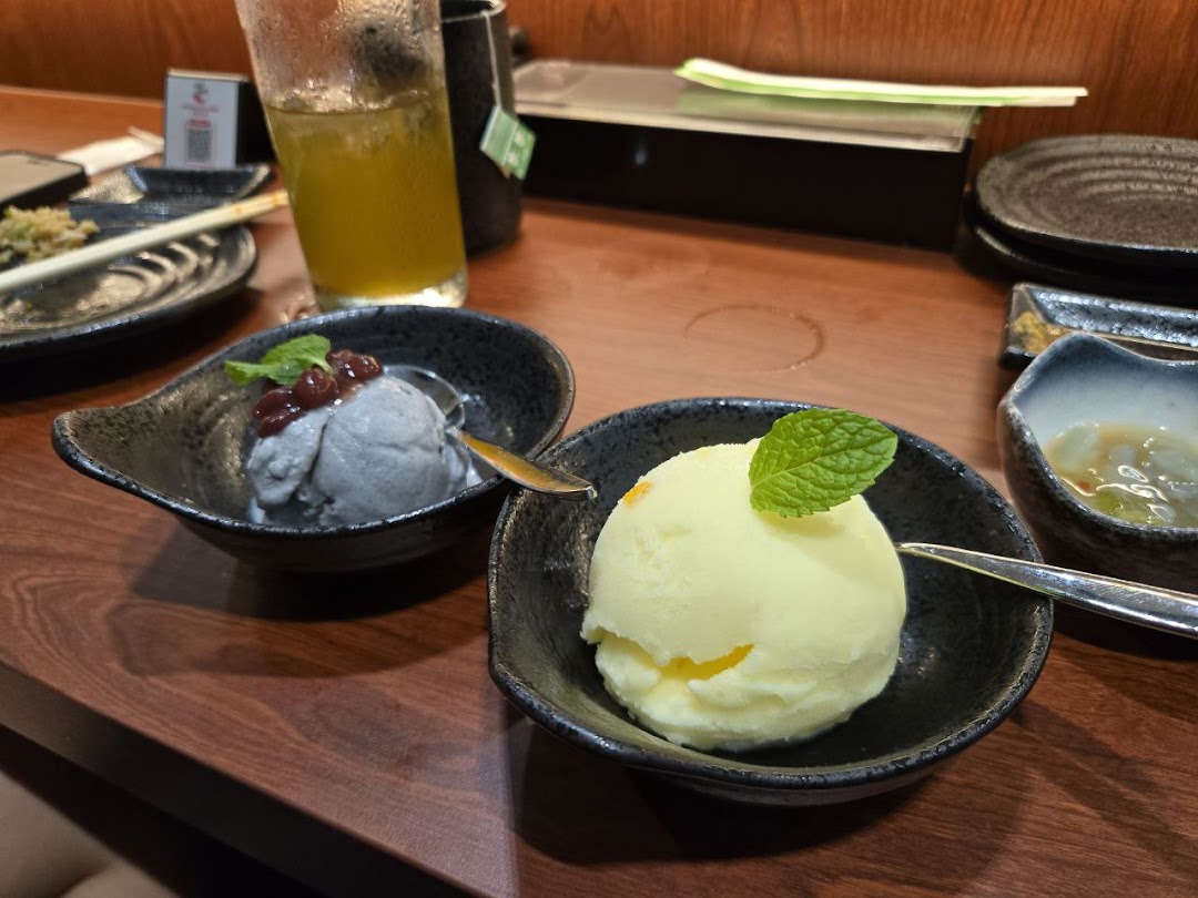 Two scoops of ice cream, one dark with red beans and one light with mint, served in bowls on a wooden table.