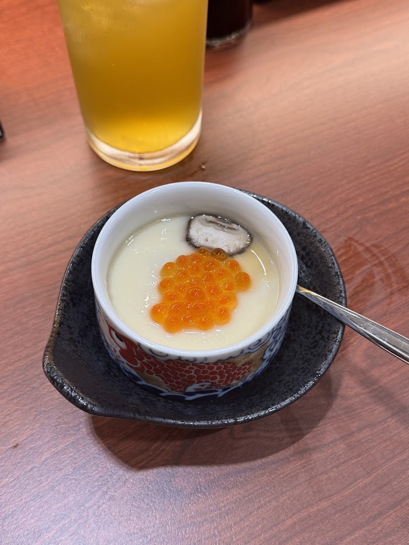 A close-up of a chawanmushi dish topped with salmon roe and mushroom, alongside a drink.