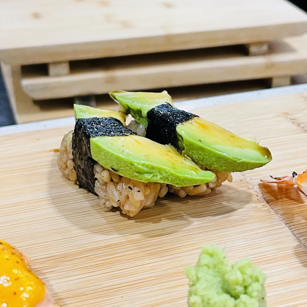 Close-up of fresh avocado sushi served on a wooden board with wasabi.