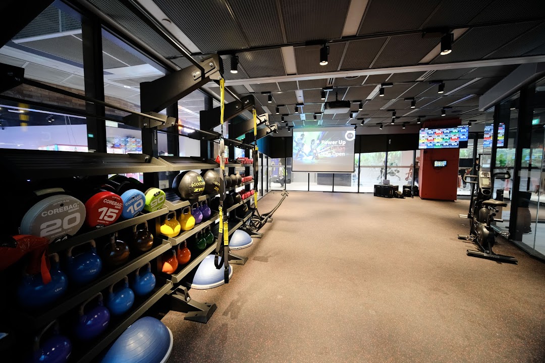 An interior view of TFX Fitness, showcasing a spacious workout area with various weights and fitness equipment.