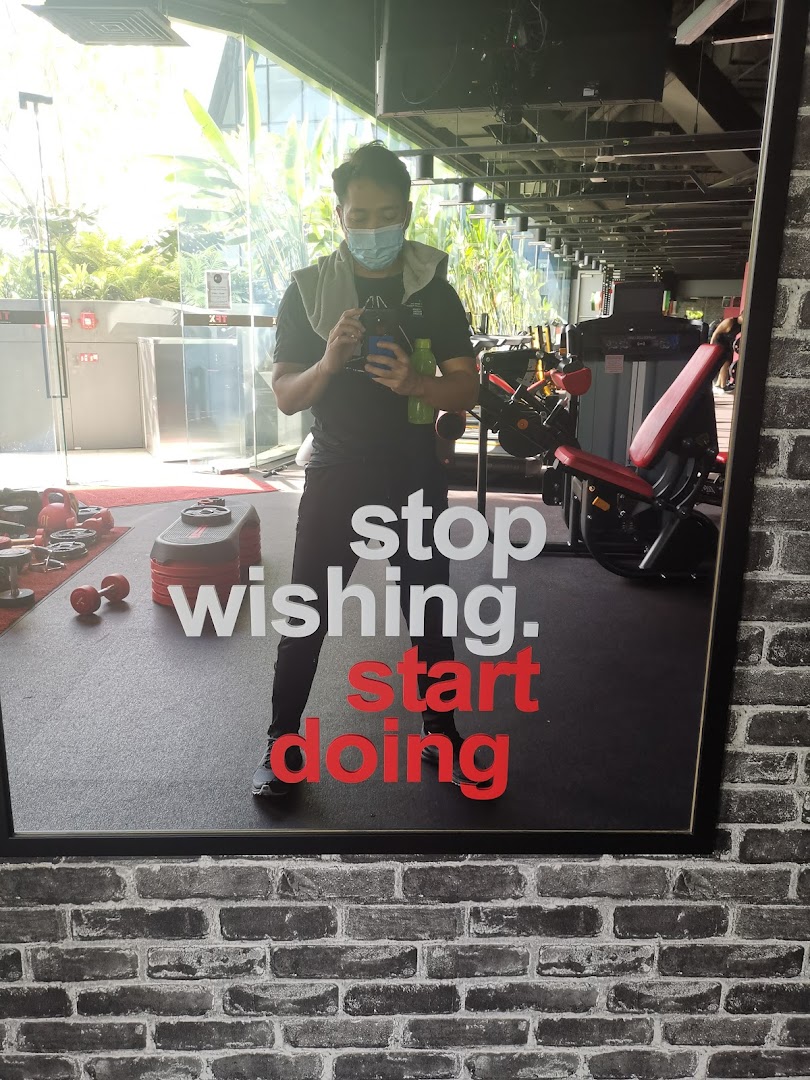 A person reflected in a gym mirror with motivational text 'stop wishing. start doing' and fitness equipment.