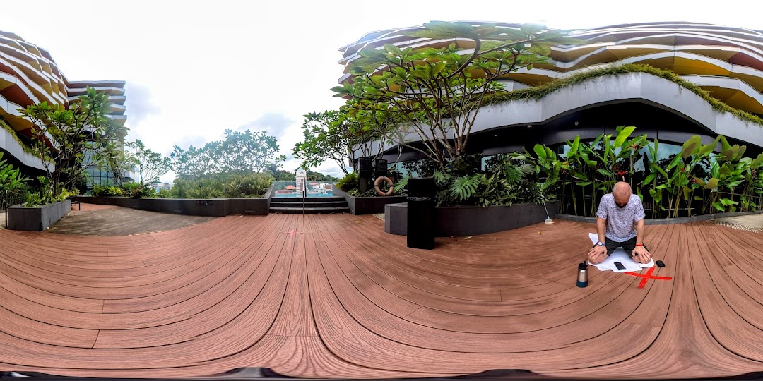 A person exercising on a spacious outdoor wooden deck surrounded by lush greenery and modern architecture.