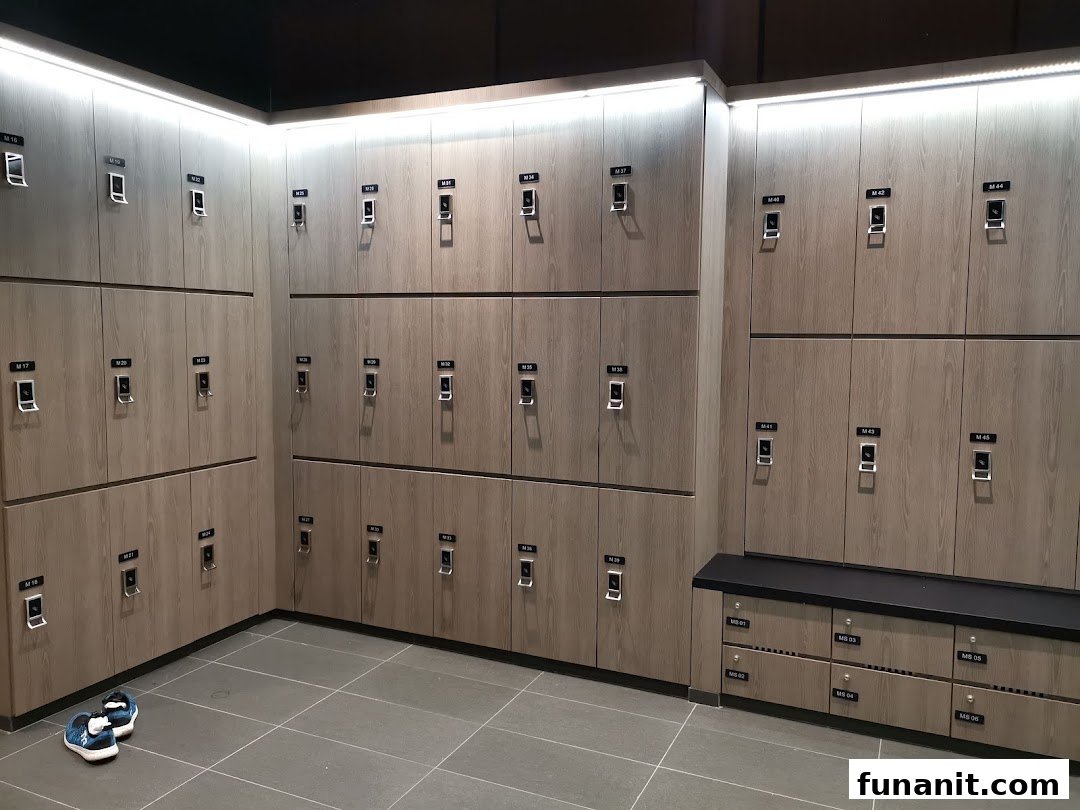 A modern, well-lit locker room with numerous wooden lockers and a bench at TFX Fitness.