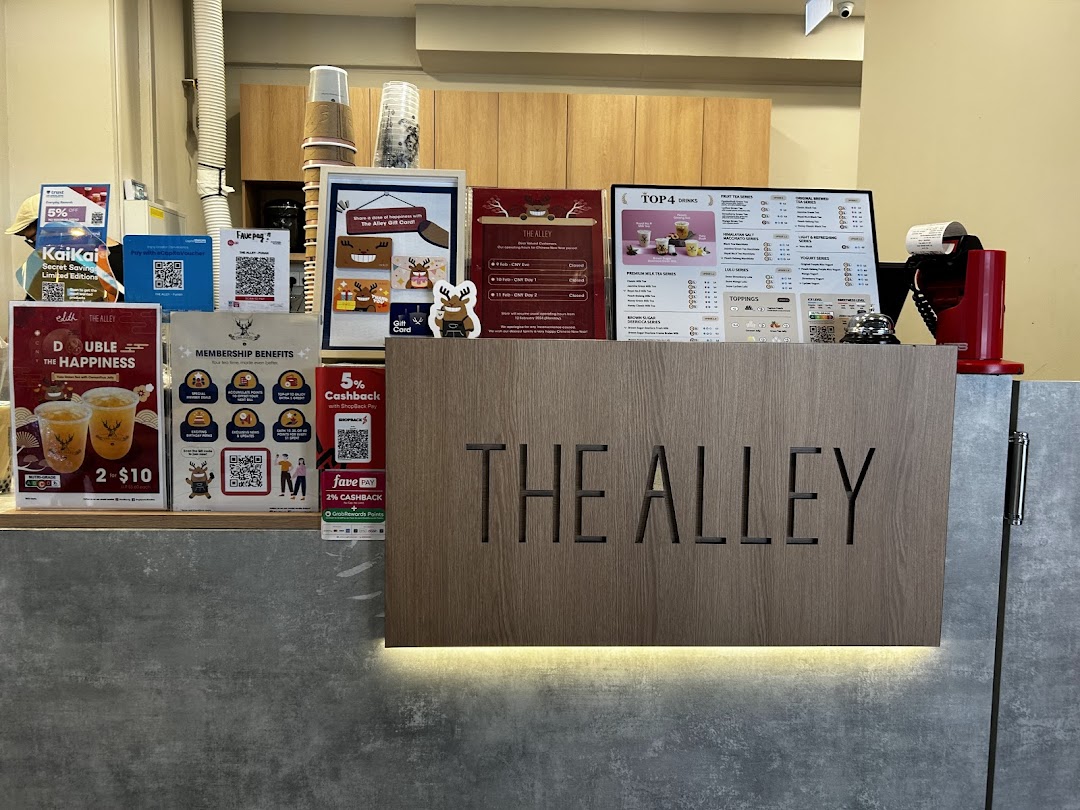 A vibrant counter display at The Alley, featuring their menu board, promotional offers, and branding.