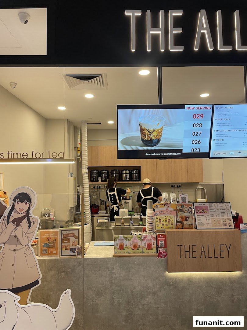 An interior shot of The Alley bubble tea shop, showing the counter, staff, and digital menu.