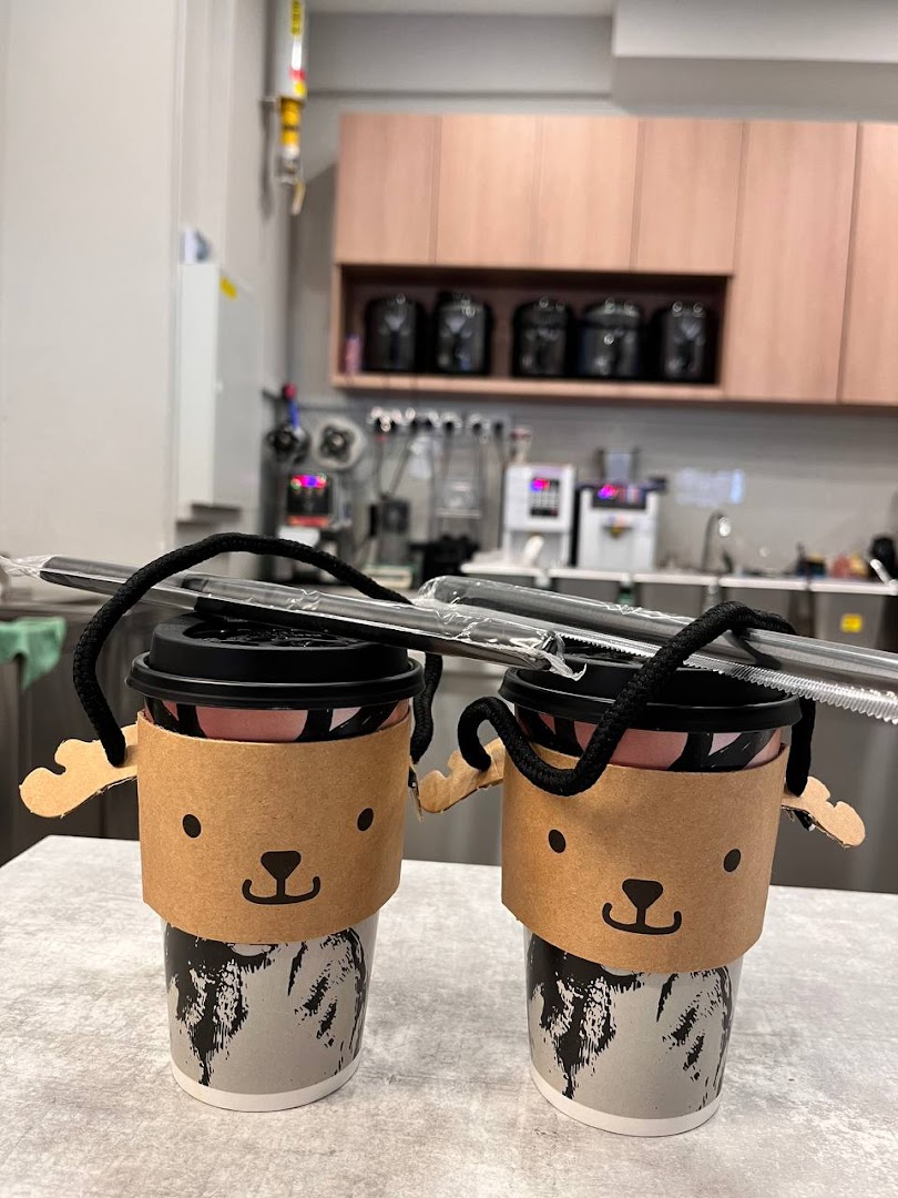 Two bubble tea cups with cute deer-themed sleeves and reusable straws on a counter.