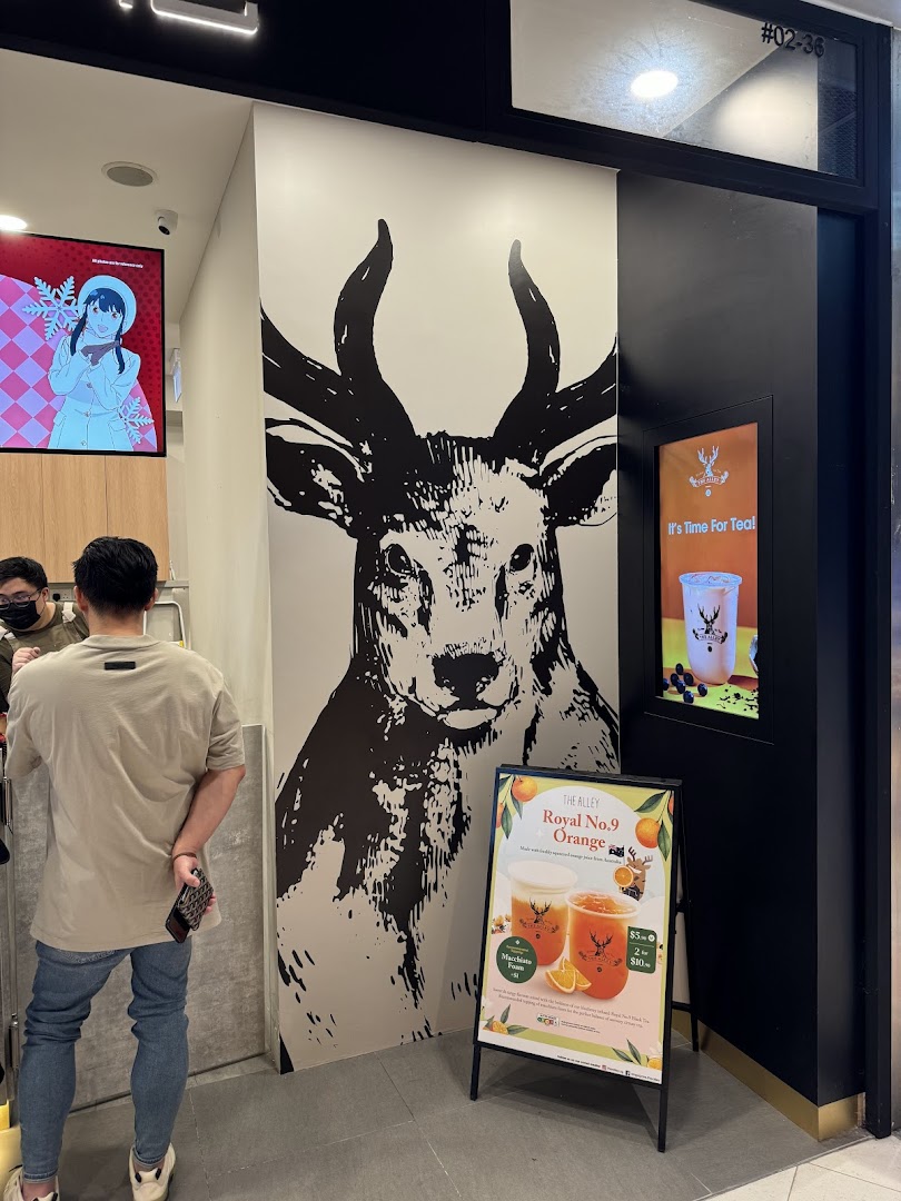 The shop front of The Alley featuring a large deer graphic, a promotional A-frame, and a customer.