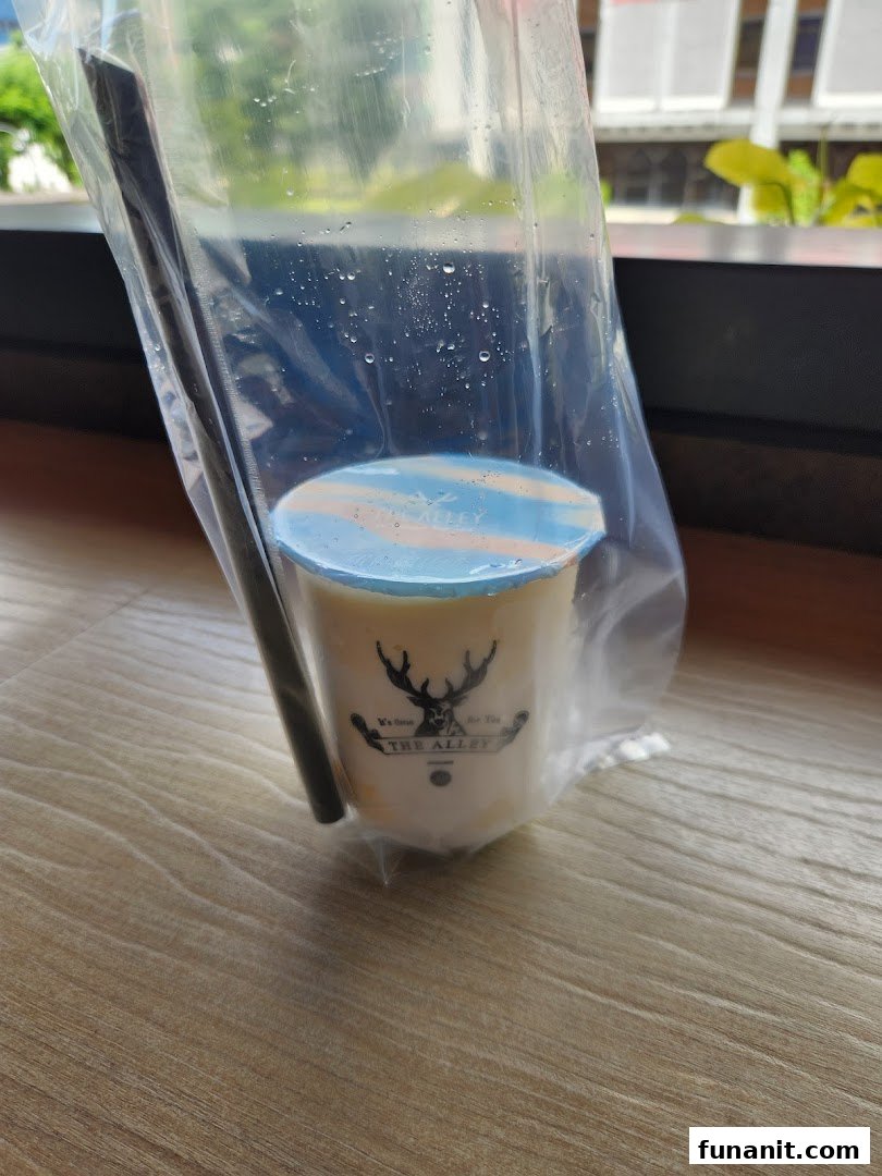 A refreshing bubble tea drink from The Alley, presented in a clear plastic bag with a straw.